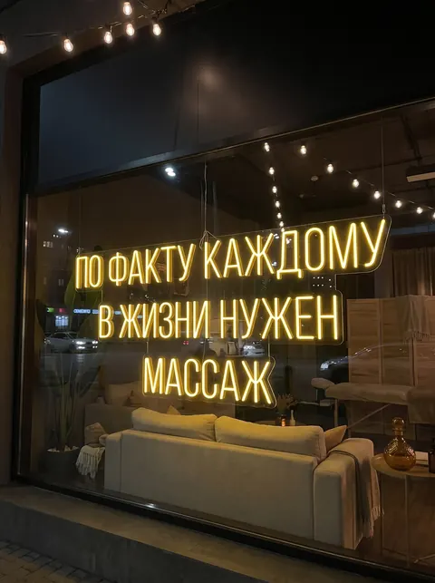 Неоновая вывеска в окне: «По факту каждому в жизни нужен массаж»